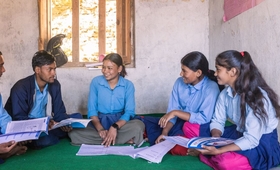 Five students sitting in a classroom with books.