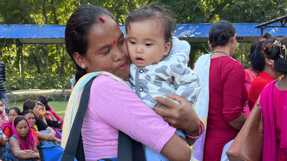 A mother hugs her baby after receiving flood relief assistance